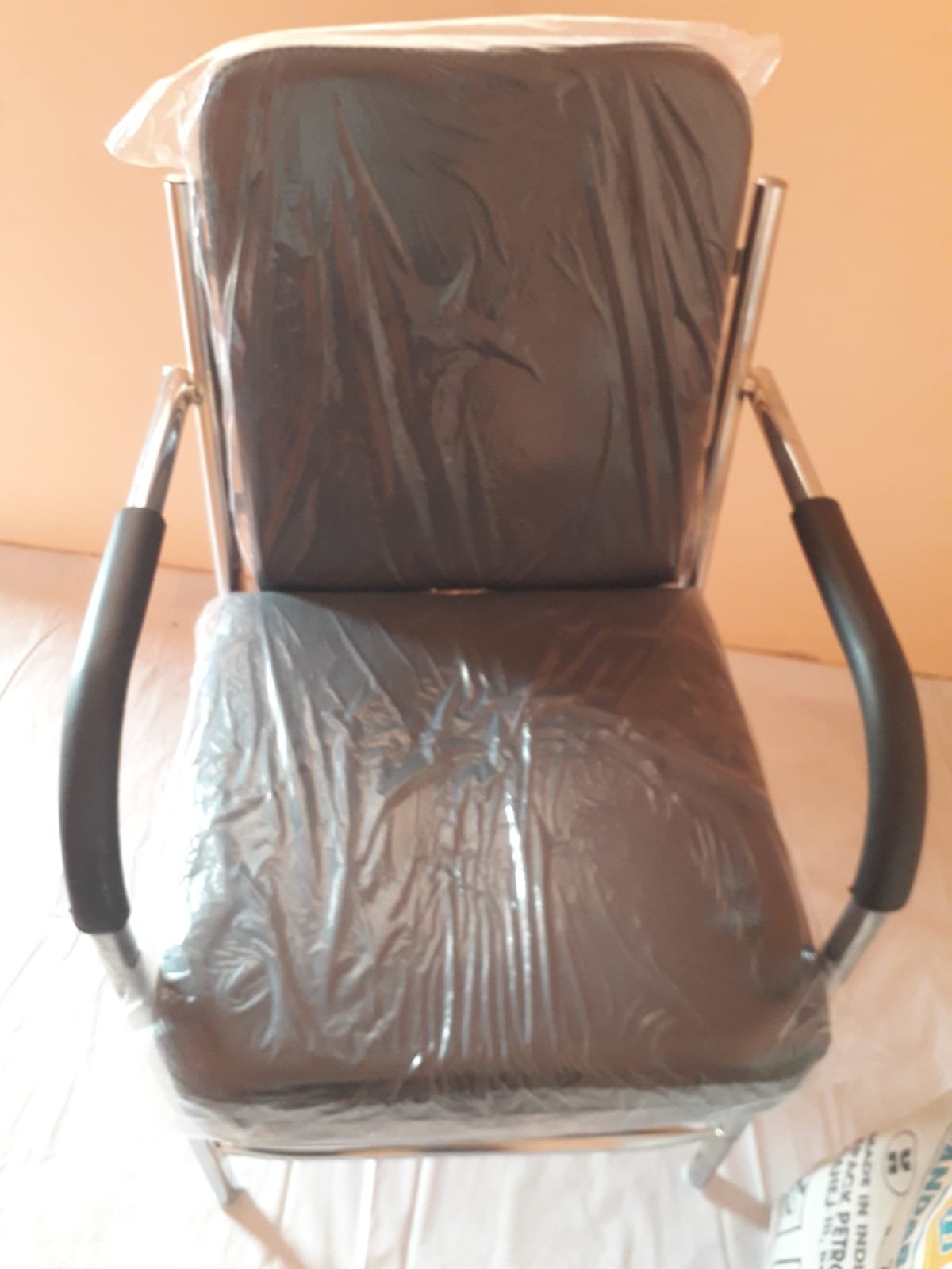 Black cushioned office visitor chair with metal frame and armrests